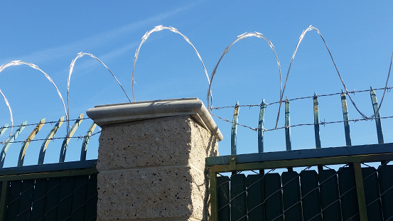 Barb wire and razor ribbon was installed atop a wrought iron fence for added security in Norwalk CA